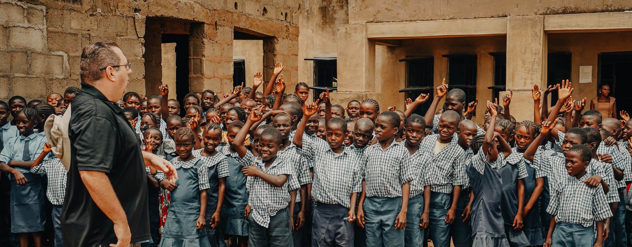 Children in a Nigerian village smiling and waving at the camera