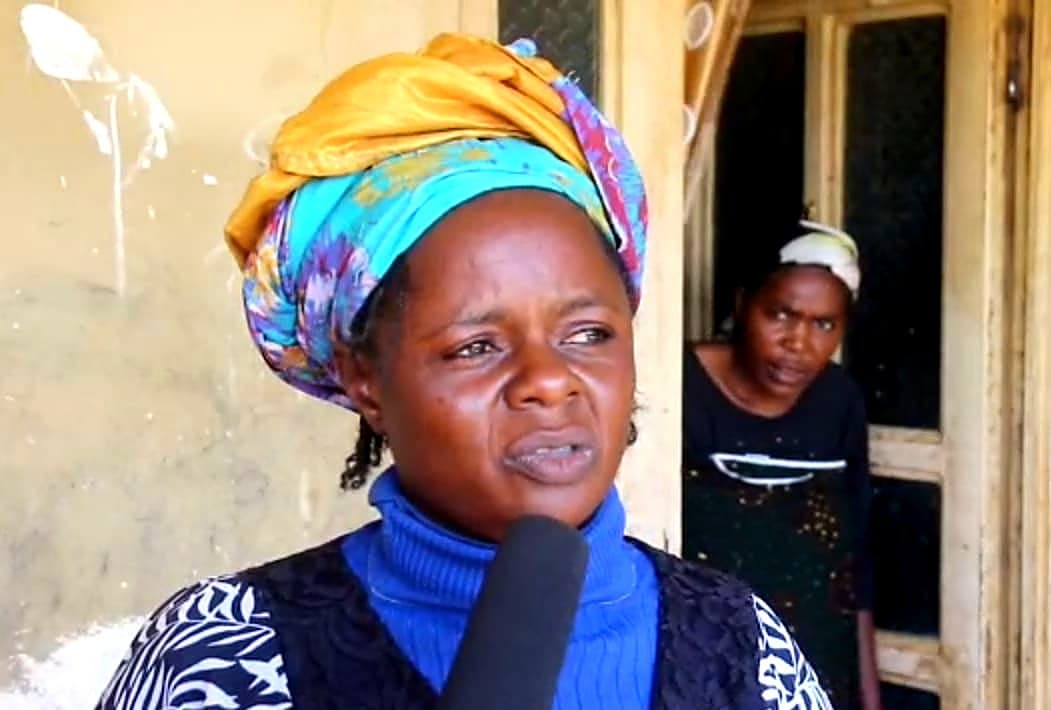 Rahila, in a headwrap, speaking to a reporter outside a home in Kajuru