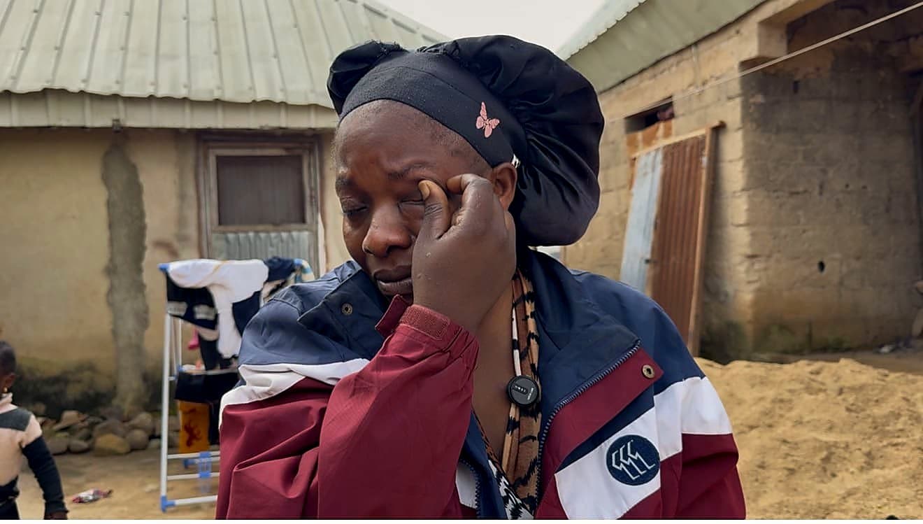Scholastica Emmanuel Hills wiping away tears outside her home in Bokkos